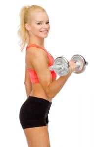 Blonde sporty woman smiling while exercising with dumbbell