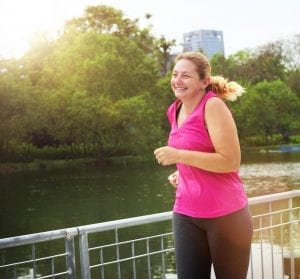 Smiling woman jogging on a bridge