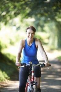 Smiling, pretty middle-aged woman cycling in the forest