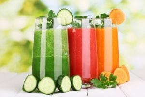 Fresh vegetable juices on wooden table, on green background