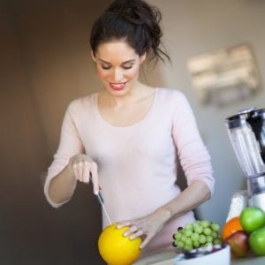 Smiling woman cutting a melon to juice