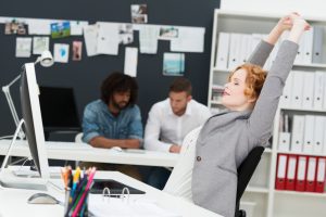 Pretty female stretching her arms above her head in the office