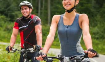 Young man and woman cycling on road in forest