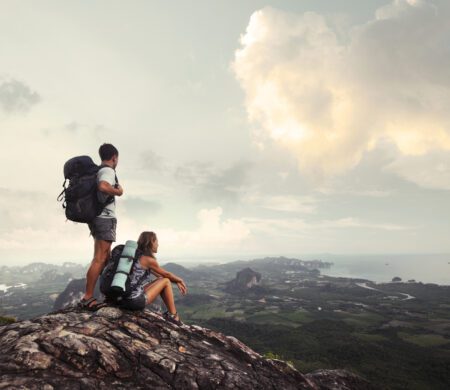 HIking couple on a mountaintop looking at the scenery below